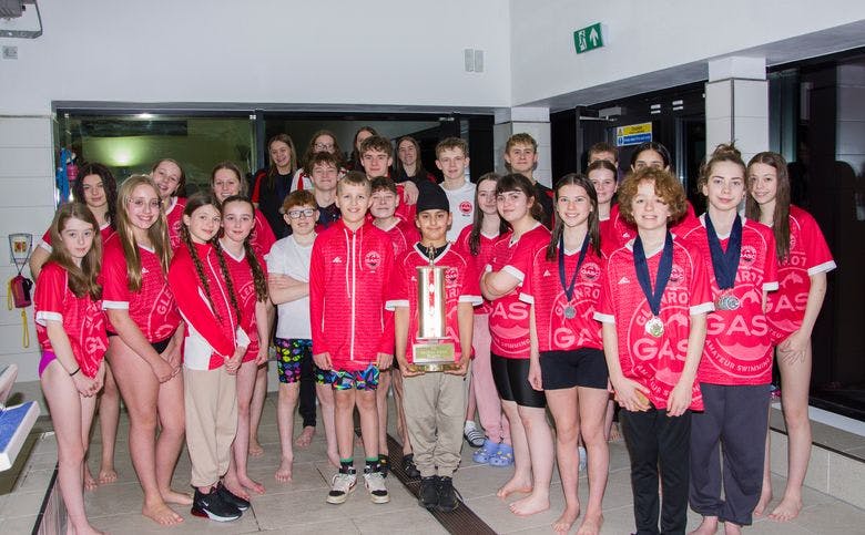A group of proud GASC swimmers triumphantly holding the Fife Championship trophy.
